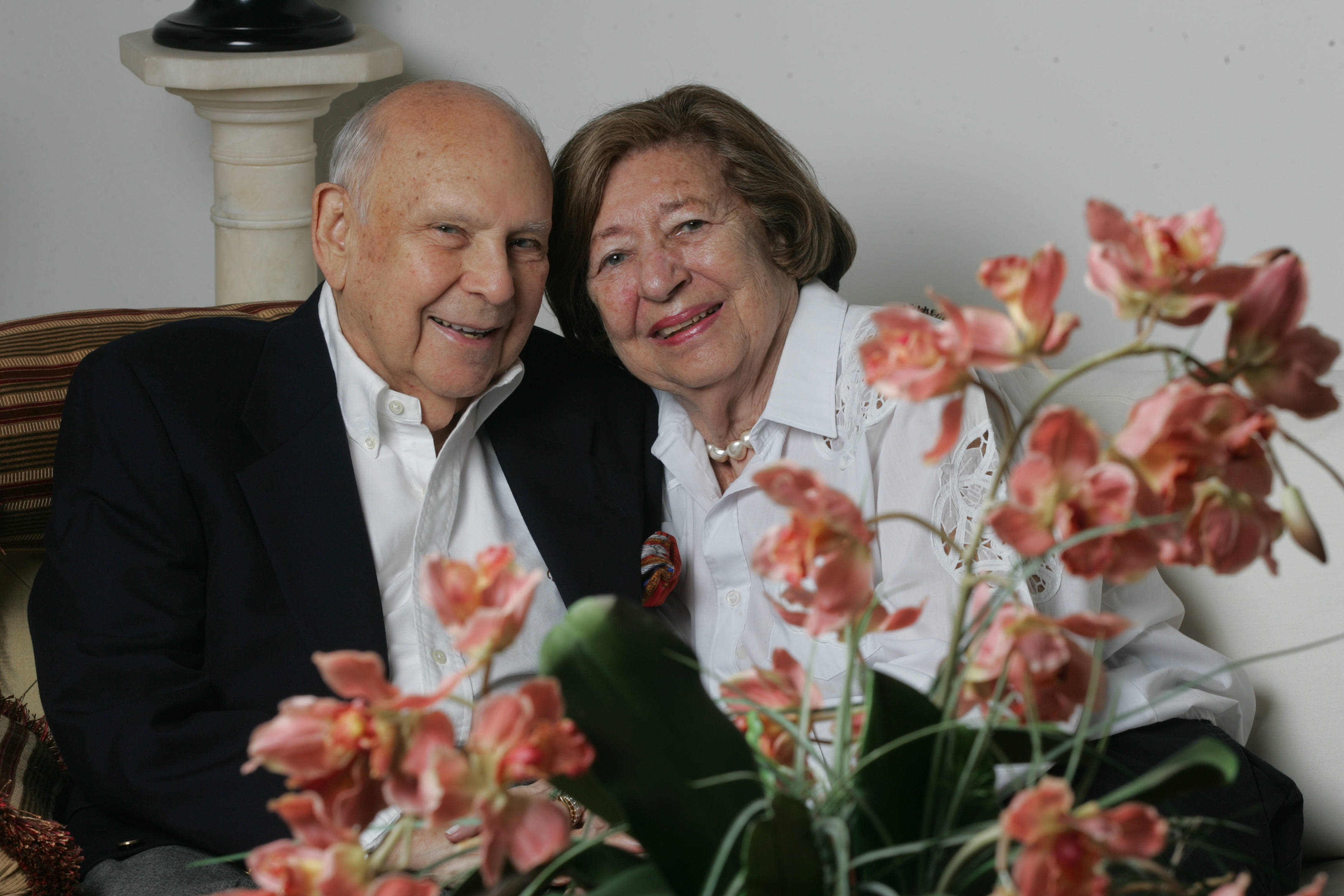 Portrait of Marvin and Sybil Weiner sitting together, the photo is framed by flowers