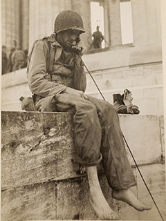 A barefooted GI talks to his command post from the monument at Montsec, France