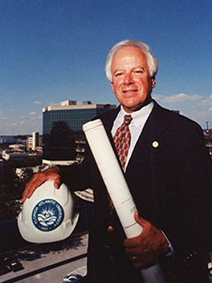 Photograph of Dr. Anthony Catanese holding a FAU construction hat and plans