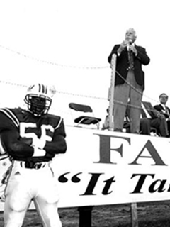 Photograph of Howard Schnellenberger speaking at a rally with FAU football player