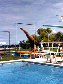 Photograph of a FAU Swimming team member diving into the pool